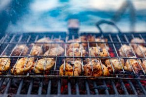 Charcoal chicken cooking with wire over the top of it