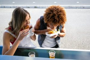 Two girls are sitting and eating charcoal chicken burgers in Sydney